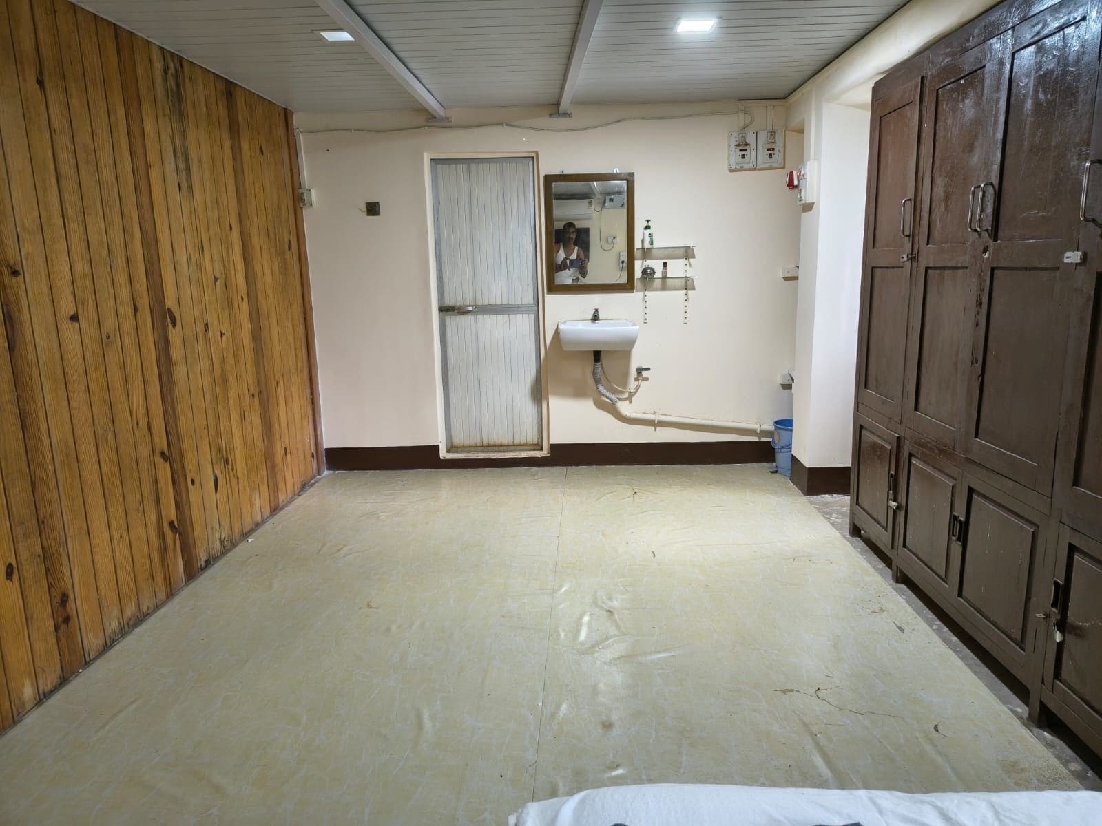 A room with a wooden wall, a white sink, and a mirror.