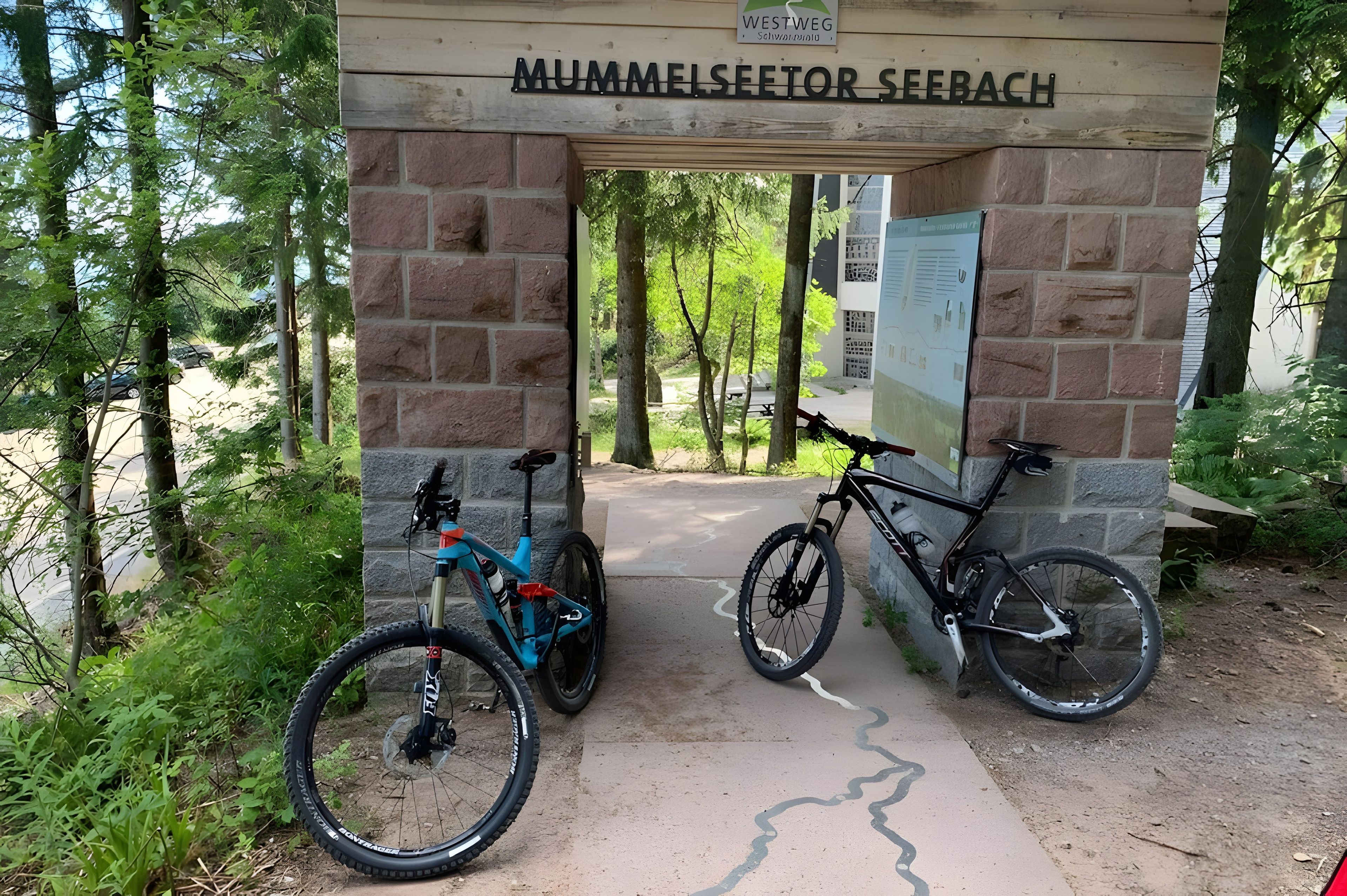 Une arche en pierre portant l’inscription « MUMMELSEETOR SEEBACH » et deux vélos garés en dessous.