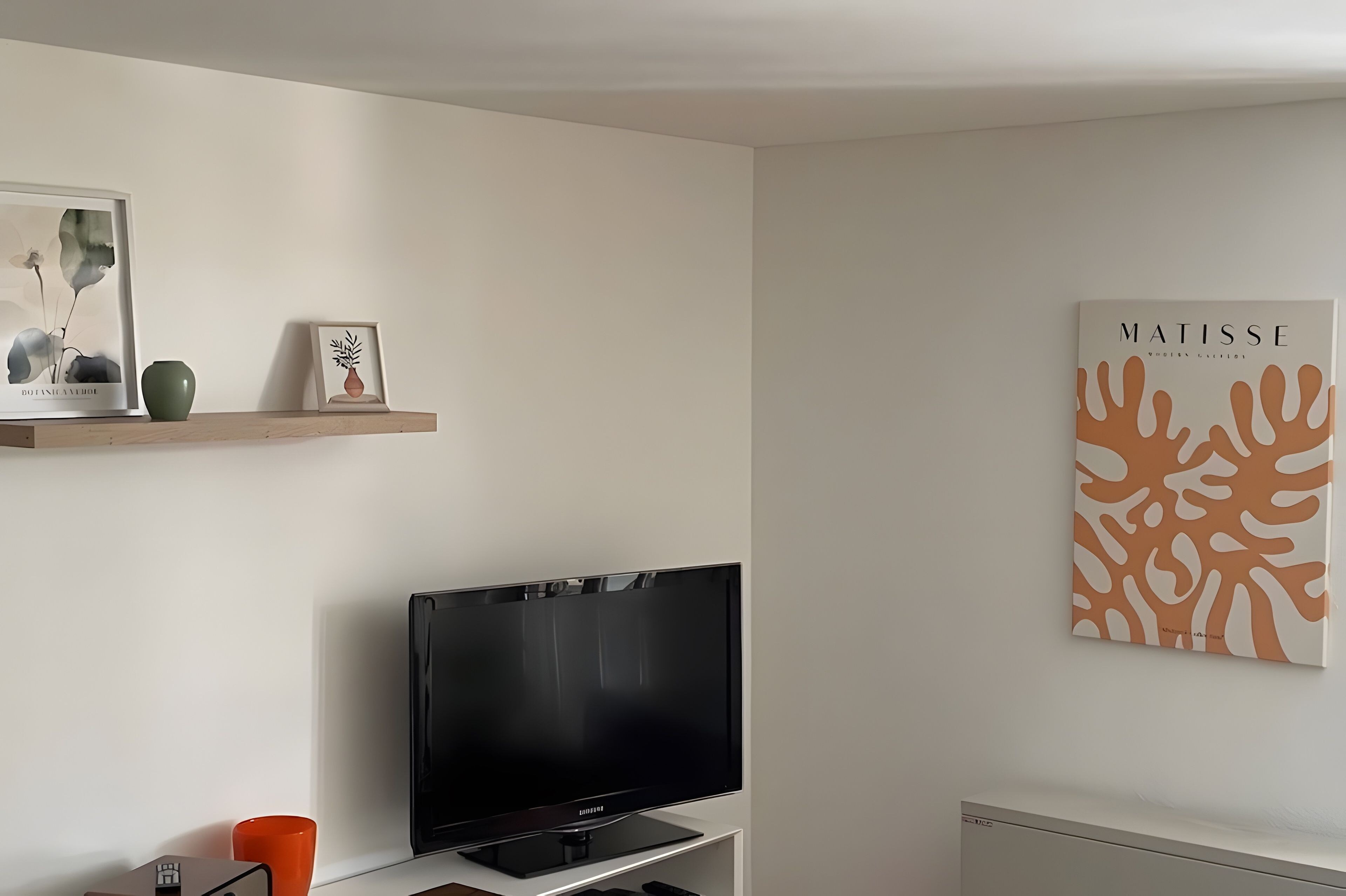 Un salon doté d’un téléviseur à écran plat, d’une estampe botanique encadrée et d’une œuvre d’art abstraite accrochée au mur.