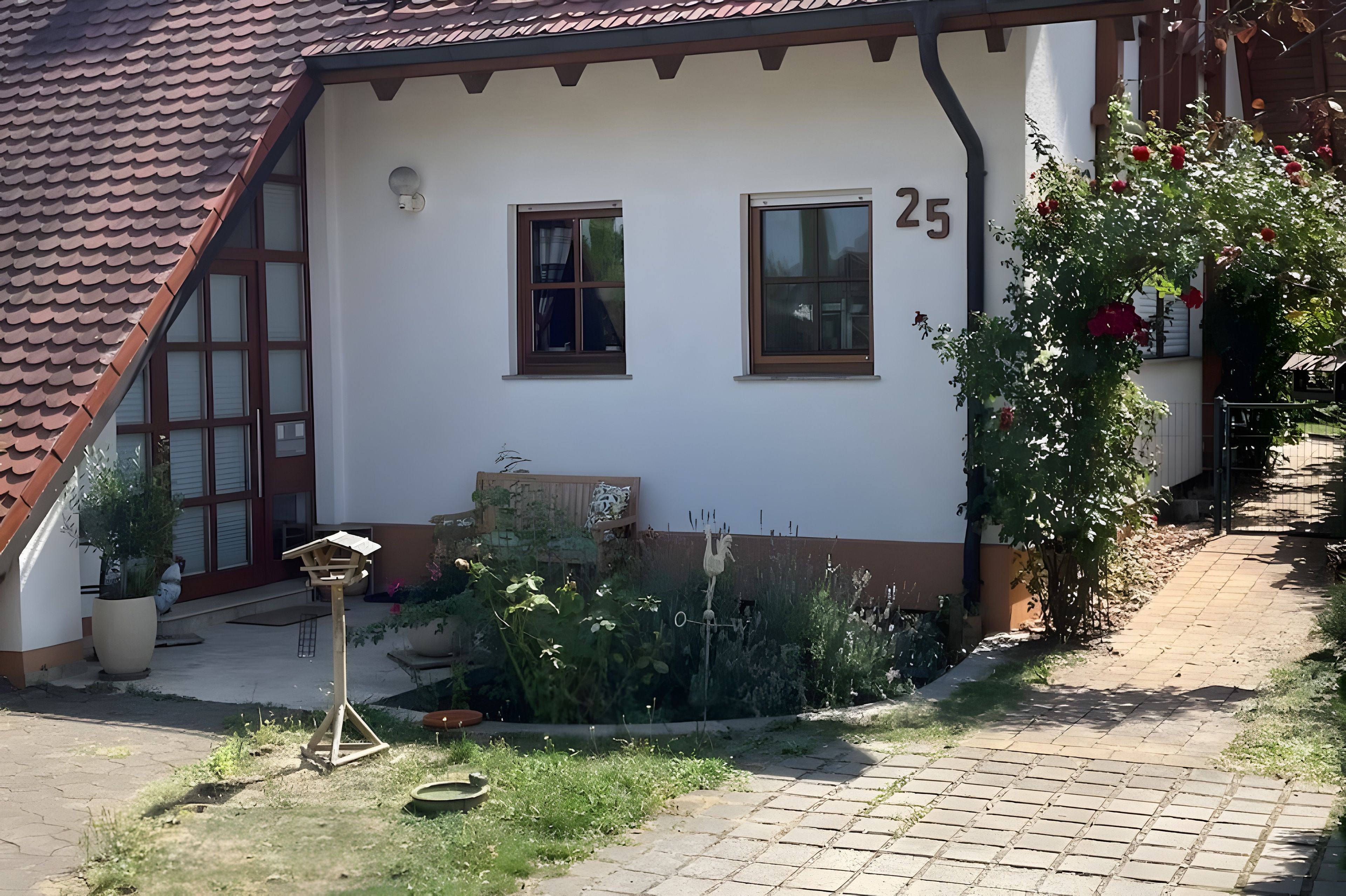 Een huis met een pannendak, twee ramen en het nummer '25' op de muur.