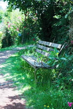A bench in a garden with a path beside it.