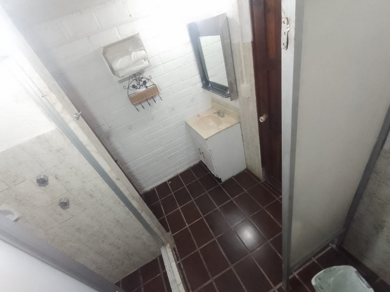 Um banheiro pequeno com pia branca, espelho e porta-toalhas.