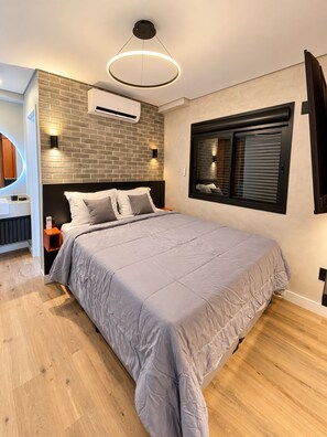 Een moderne slaapkamer met een groot bed, een ronde plafondlamp, een airconditioning en een raam met zonwering.