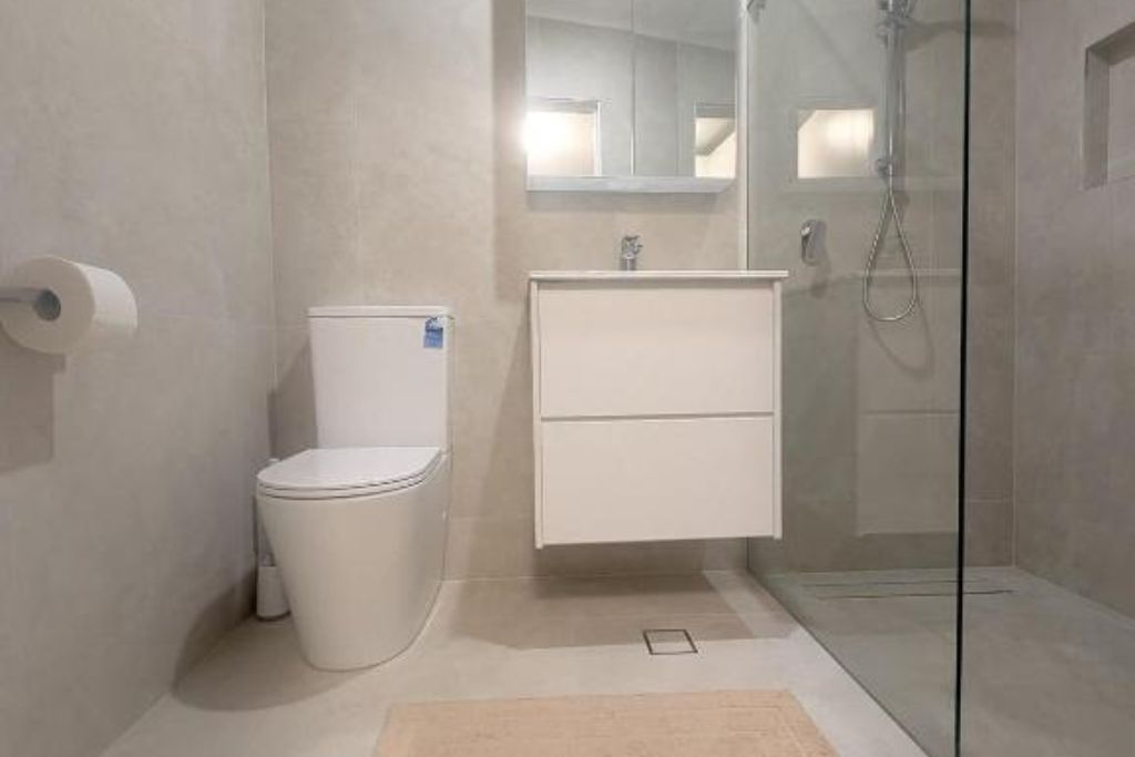 A modern bathroom with a toilet, a sink, and a shower enclosure.