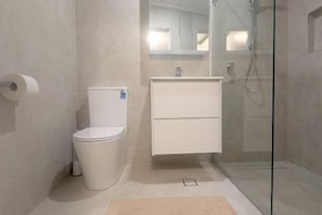 A modern bathroom with a toilet, a sink, and a shower enclosure. - Fresh & Cosy Beachside Escape (Curl Curl)