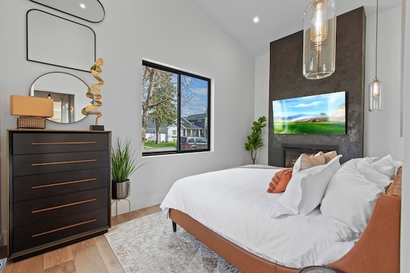 Une chambre à coucher avec un lit, une commode, une télévision et une cheminée.