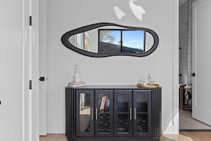 Un intérieur moderne avec un meuble console noir, un miroir et une porte donnant sur une autre pièce.