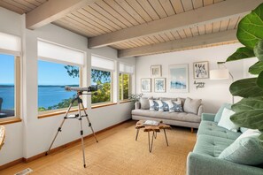 Ein Wohnzimmer mit Teleskop, einer Couch und Meerblick.