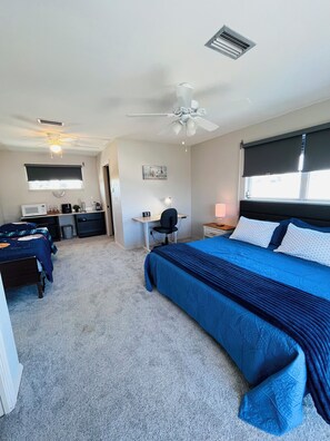 Ein Schlafzimmer mit Bett, Schreibtisch, Stuhl und Deckenventilator.
