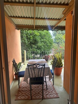 An outdoor patio with a table and chairs, surrounded by potted plants and a view of greenery. - Casa Baldoria Tropical Escape (Cabrera)