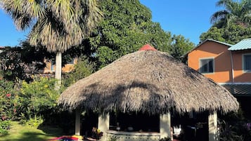 A thatched-roof structure with a pool in the foreground.