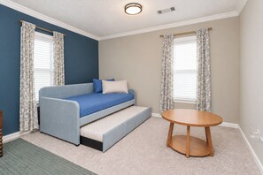 Une chambre avec un canapé-lit, une table ronde en bois et des rideaux.