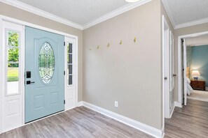 Un couloir avec une porte bleu clair, des murs de couleur beige et un plancher en bois.