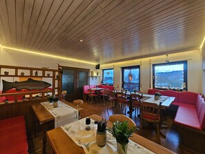 Un restaurante con techo de madera, asientos rojos y ventanas amplias con vistas a la ciudad.