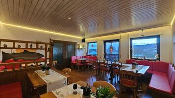 Un restaurante con techo de madera, asientos rojos y ventanas amplias con vistas a la ciudad.