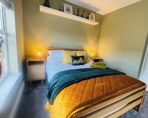 Una camera da letto con un letto, comodini, una finestra e uno scaffale con oggetti decorativi.