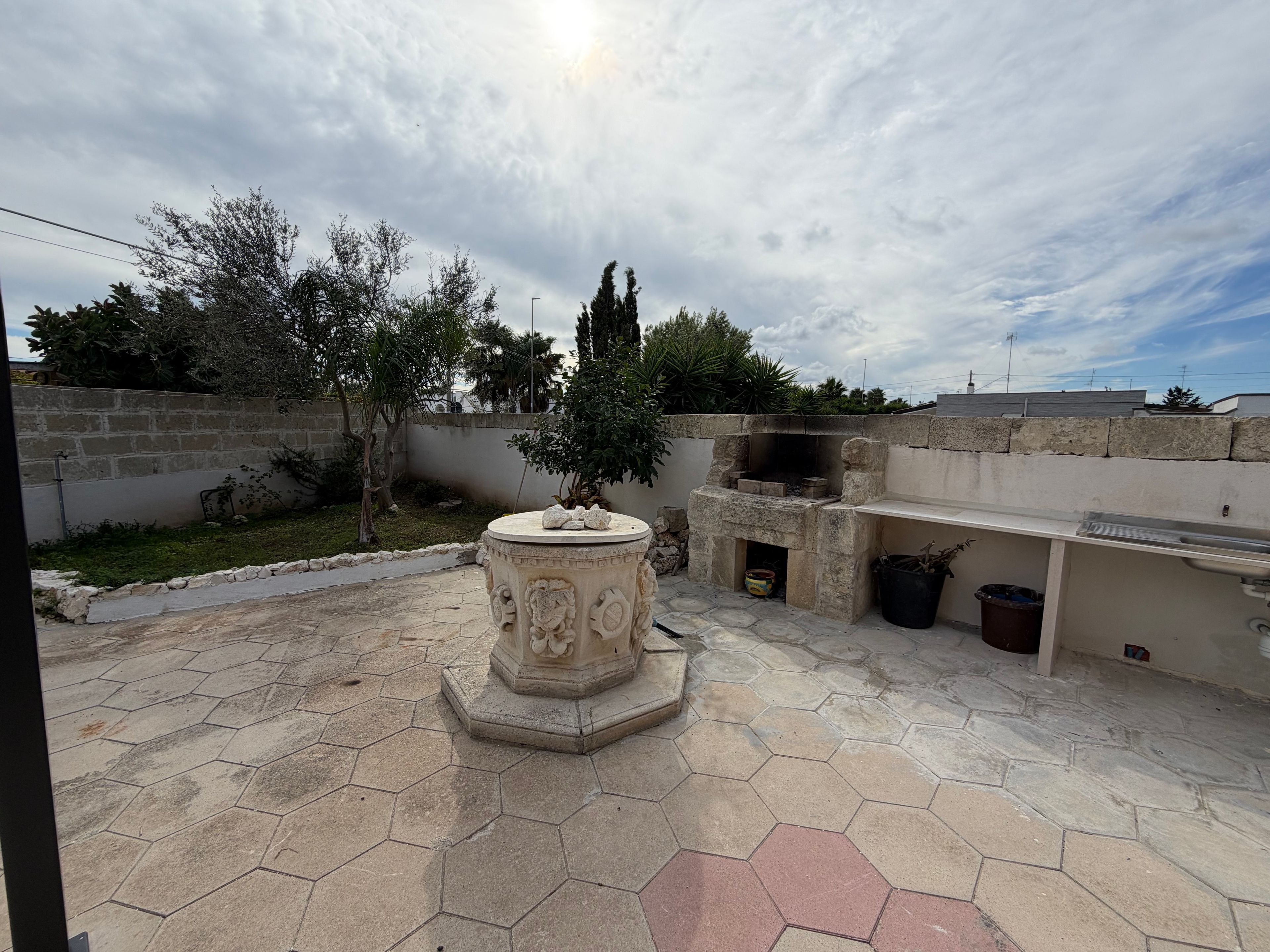 Une terrasse dotée d’un foyer en pierre, d’un barbecue encastré et d’un sol carrelé en forme d’hexagone.