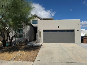 A modern two-story house with a garage, a driveway, and a tree. - Deluxe Las Cruces Retreat: Mountain Views, Secure Outdoor Oasis, Modern Comforts (Las Cruces)