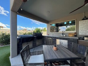 Une terrasse extérieure équipée d’une table à manger, de chaises, d’un barbecue et d’un coin cuisine.