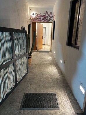 A hallway with a textured wall, a cactus, and a door leading to another room. - New Listing (La Paz)