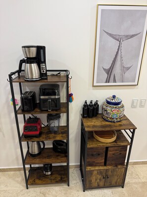 Cuina amb cafetera, torradora, batedora i un bocal decoratiu sobre una balda de fusta.