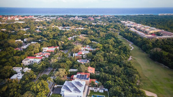 An aerial view of a residential area with houses, a golf course, and a body of water. - New Listing (Playa del Carmen)