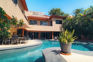 A swimming pool with a patio area, surrounded by a building with multiple windows and a balcony. - New Listing (Playa del Carmen)