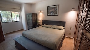 A bedroom with a bed, bedside table, lamp, wardrobe, and a framed picture on the wall. - New Listing (Playa del Carmen)