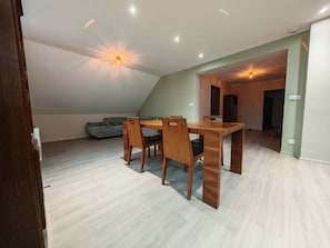 Un comedor con una mesa y sillas de madera, un sofá gris y una lámpara en el techo.