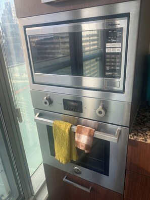 Un horno de acero inoxidable con panel de control digital, un microondas integrado y una campana extractora de acero inoxidable.