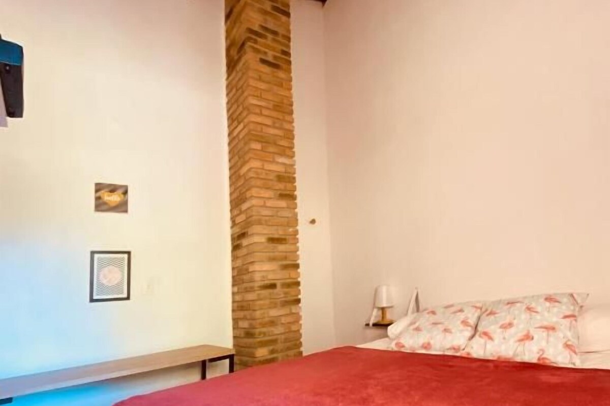 A bedroom with a bed, a stone wall, and a nightstand.