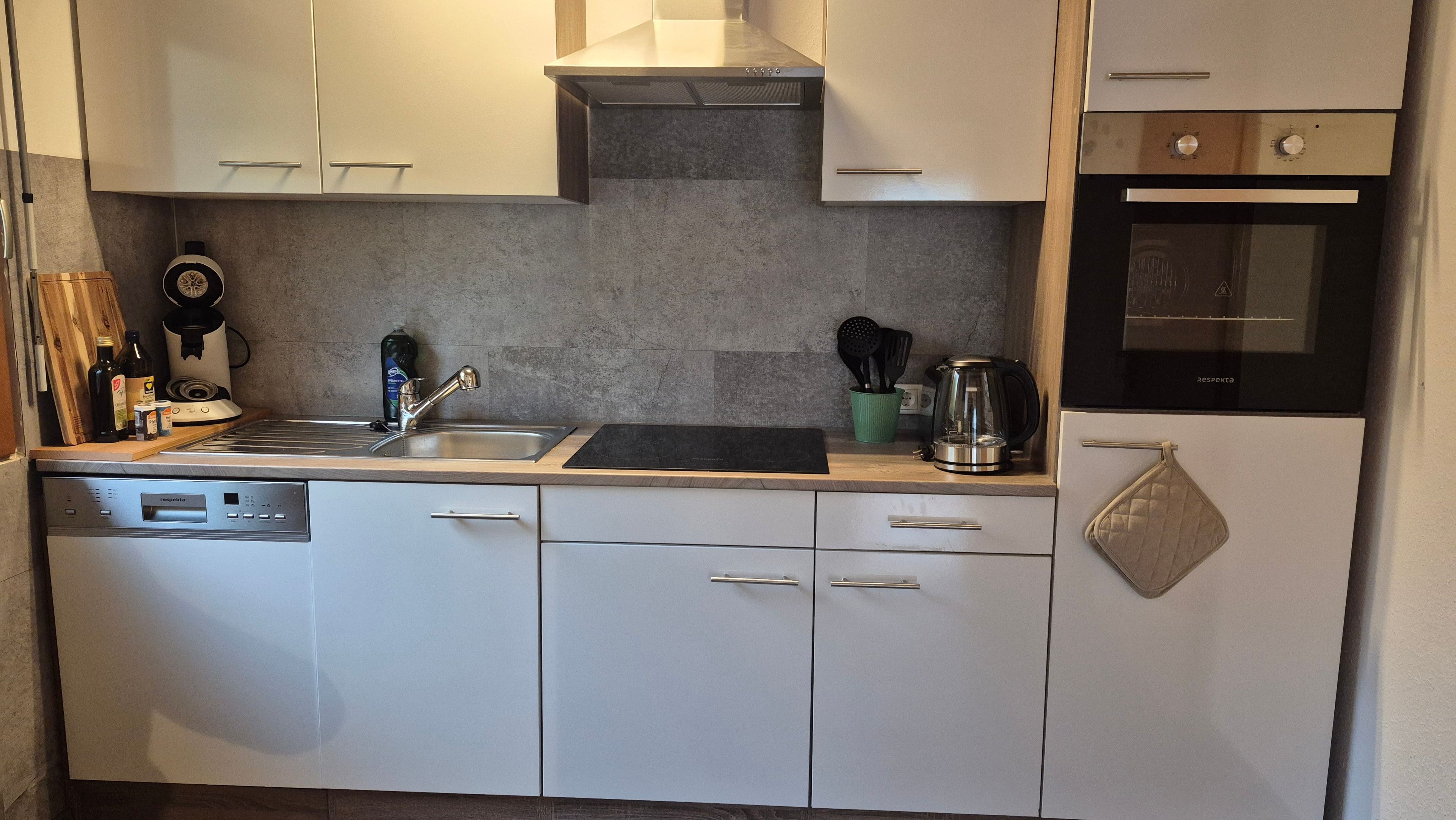 A kitchen with a dishwasher, stove, oven, and a coffee maker.