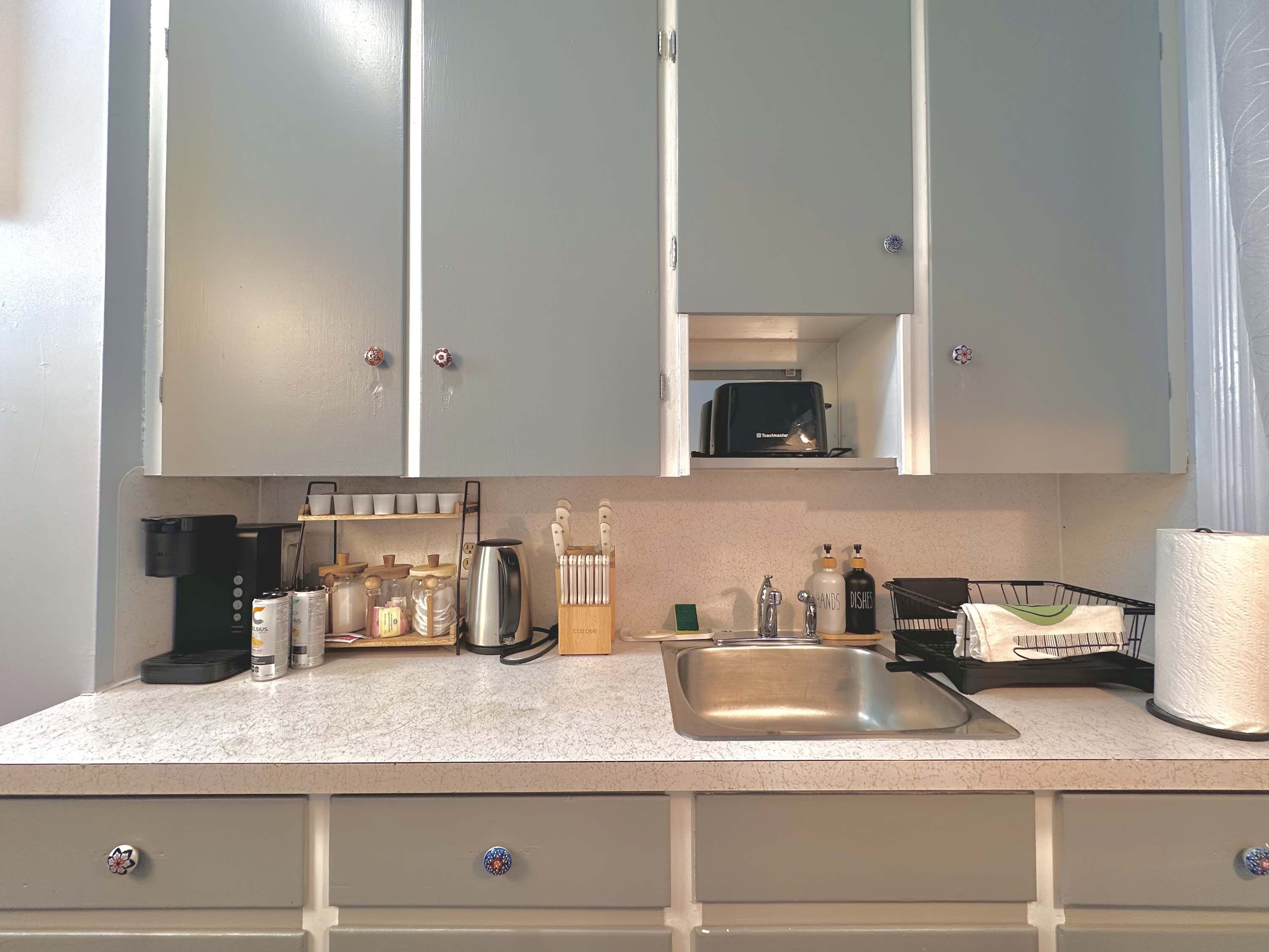 A kitchen with a countertop, sink, cabinets, and a toaster.