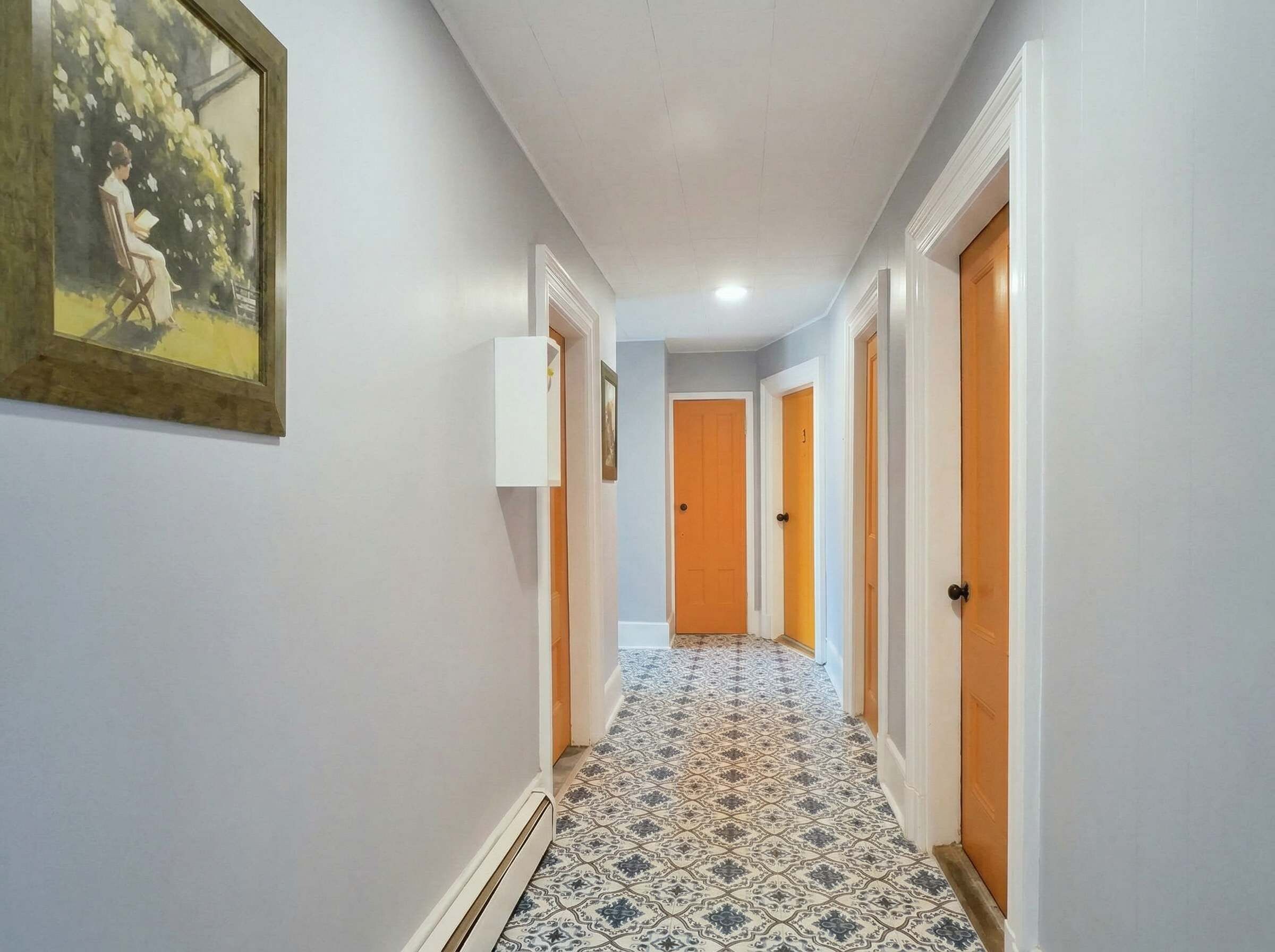 A hallway with patterned flooring, white walls, and doors leading to rooms.