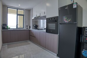 Cozinha moderna com forno embutido, geladeira e janela que proporciona luz natural.
