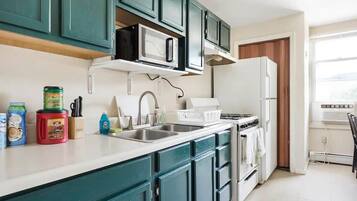 A kitchen with teal cabinets, a microwave, a stove, and a refrigerator.