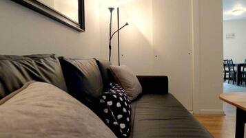 A modern living area with a sofa, a floor lamp, and a dining table.