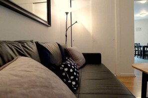 Et moderne opholdsområde med sofa, gulvlampe og spisebord.
