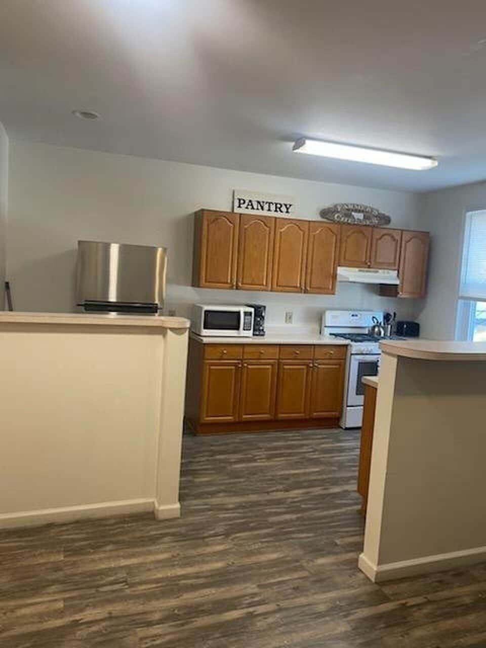 A kitchen with wooden cabinets, a microwave, and a stove.