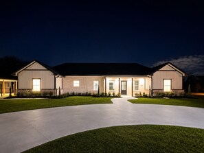 Een herenhuis met twee verdiepingen, een centrale ingang, een oprit en een verzorgd gazon.