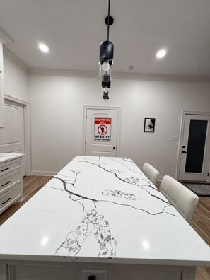 Een moderne keuken met een marmeren aanrechtblad, een hanglamp en een bord met de tekst 'Verboden toegang'.
