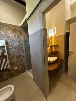 Casa de banho moderna com divisória de vidro, sanita, lavatório e zona de duche.