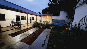 Un bâtiment moderne doté d’un patio couvert, avec une moto garée à l’extérieur et une petite piscine.