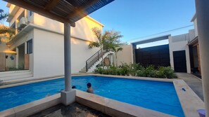 Une piscine avec un escalier menant à un bâtiment, le tout entouré de verdure.
