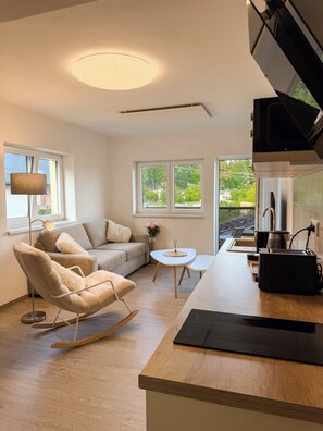 Eine moderne Küche mit Holzarbeitsplatte, eingebautem Backofen und Fenster mit Blick auf einen Garten.