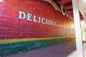 Un mur de briques sur lequel on a peint en blanc les mots « DÉLICIEUX ET ».