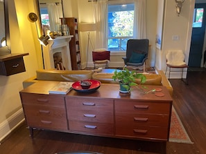 Un salon chaleureux avec un meuble en bois, un canapé, un fauteuil et une plante en pot.