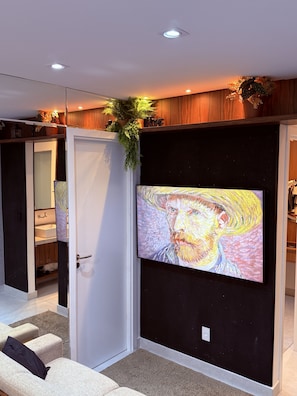 Een moderne kamer met een groot schilderij, een witte deur en een plant.