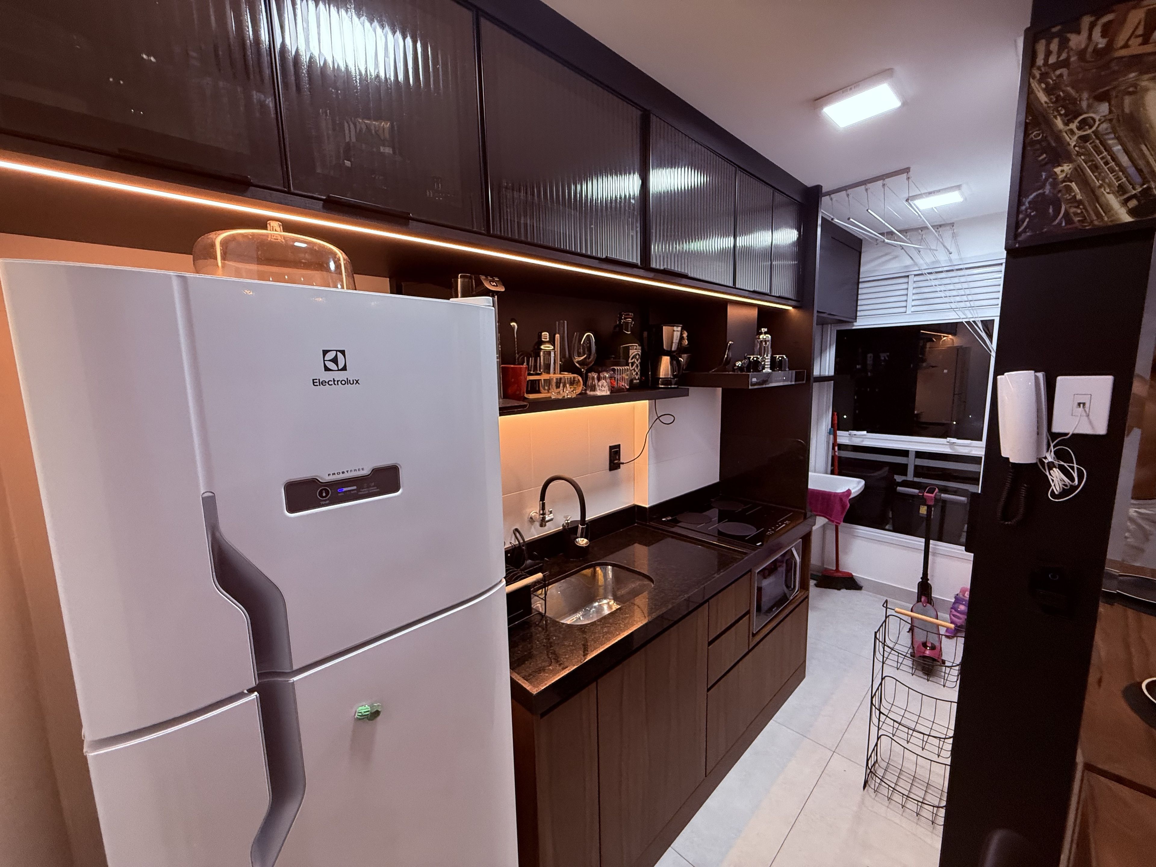 A modern kitchen with a white refrigerator, stainless steel appliances, and dark cabinetry.