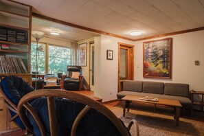 A cozy living room with a sofa, a chair, a coffee table, and a bookshelf. - Vintage charm, giant yard & hot tub in "The Creek" (Roberts Creek)